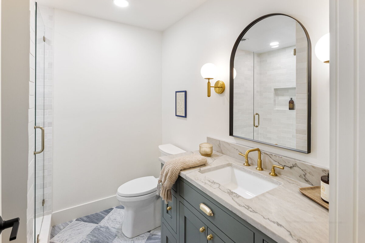 White bathoom with decorative blue tile floor, marble sink, large black mirror