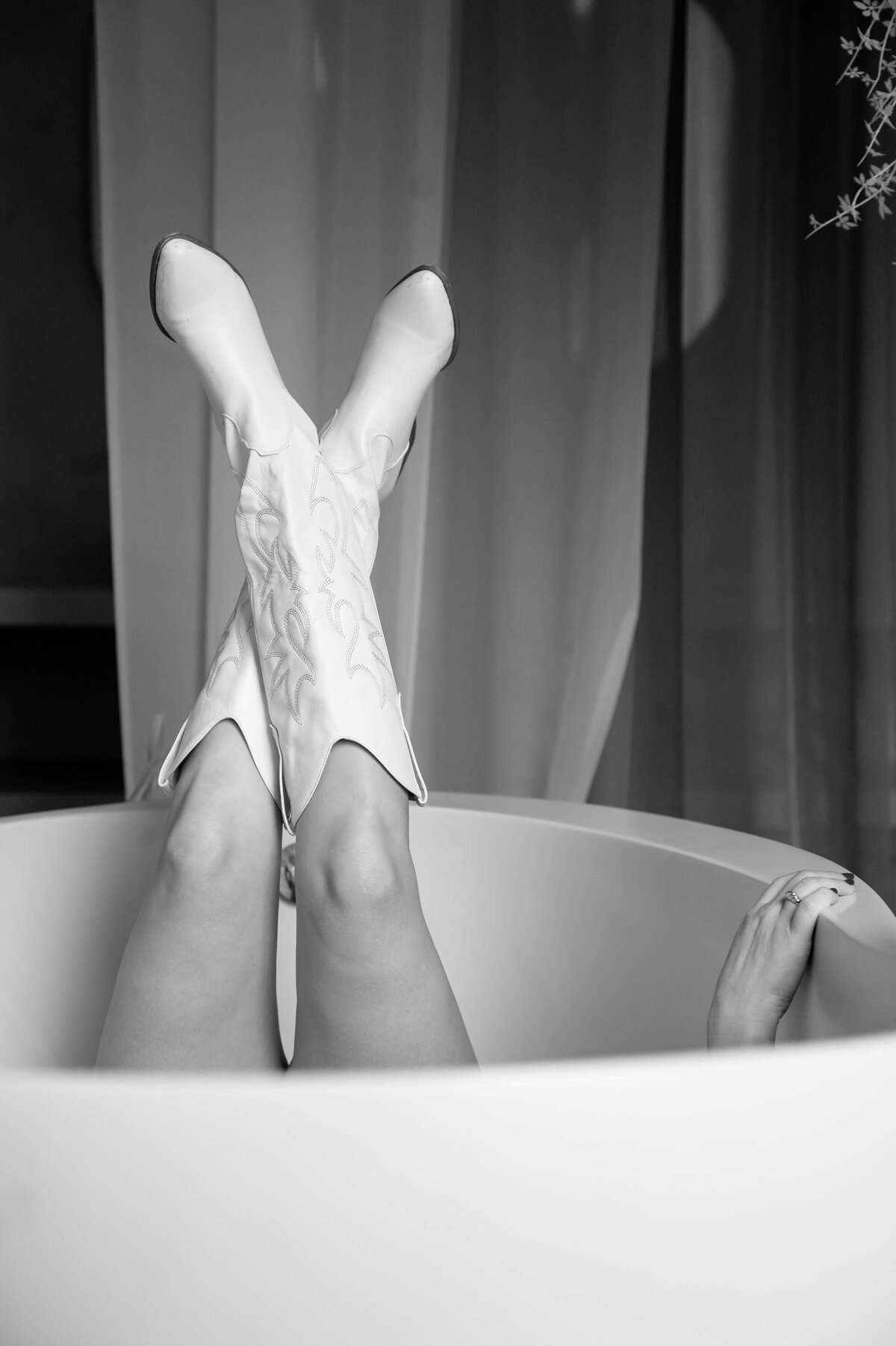 woman laying in a bathtub with her feet up wearing cowboy boots