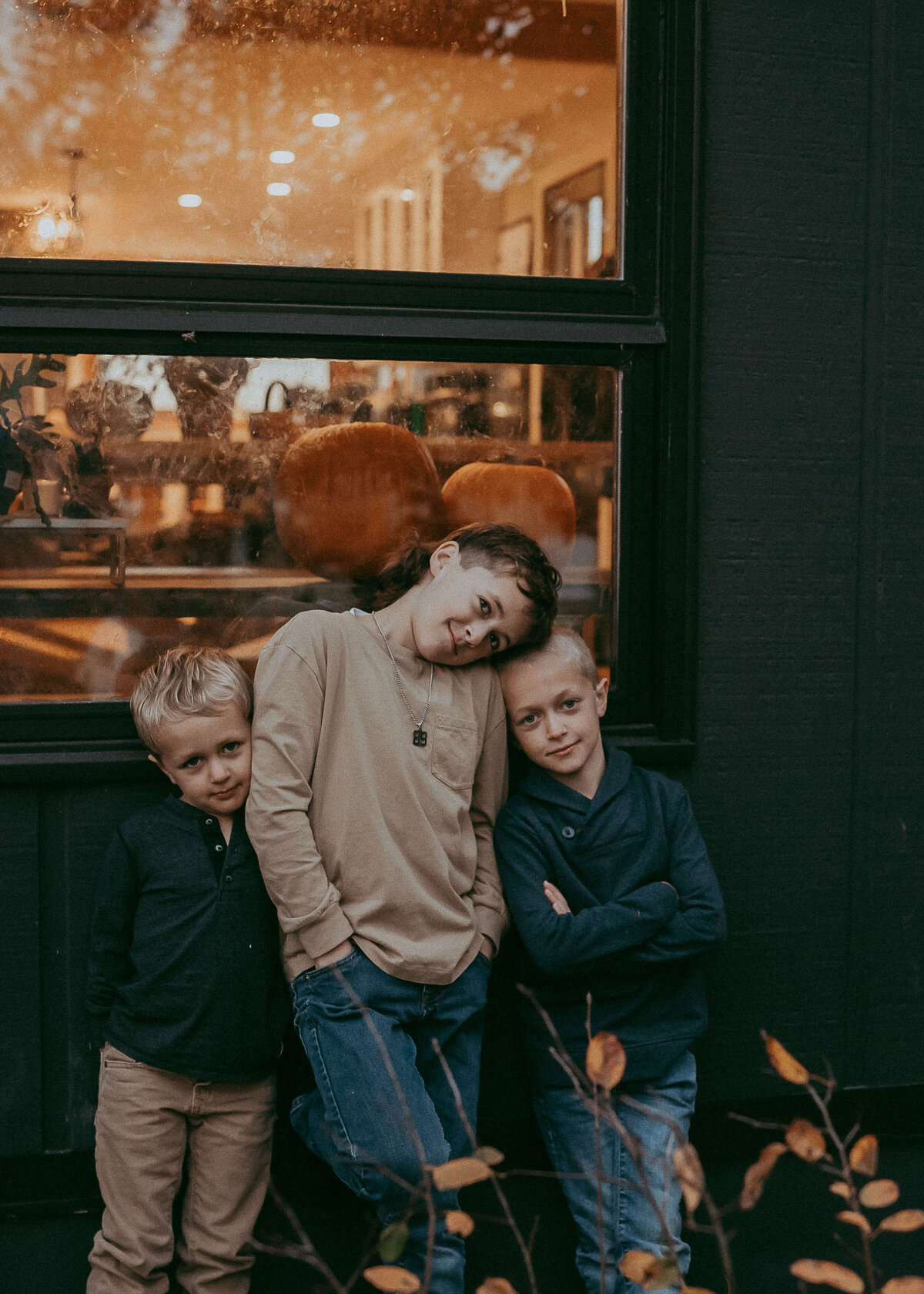 Three Brothers cuddle together during an autumn photo session, while the light coming in from their window, paints a very cool backdrop.