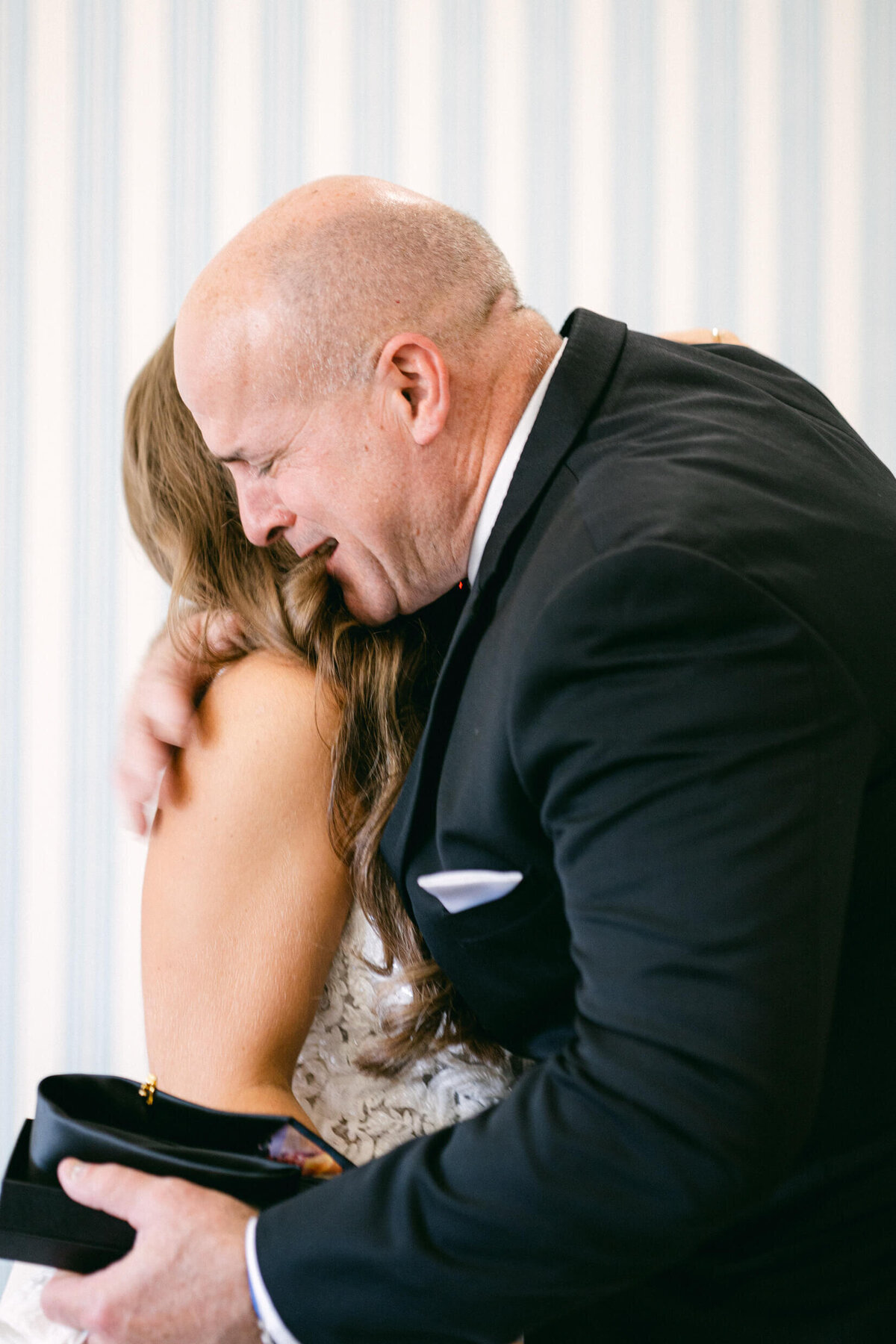 A wedding photo of the bride and her dad hugging