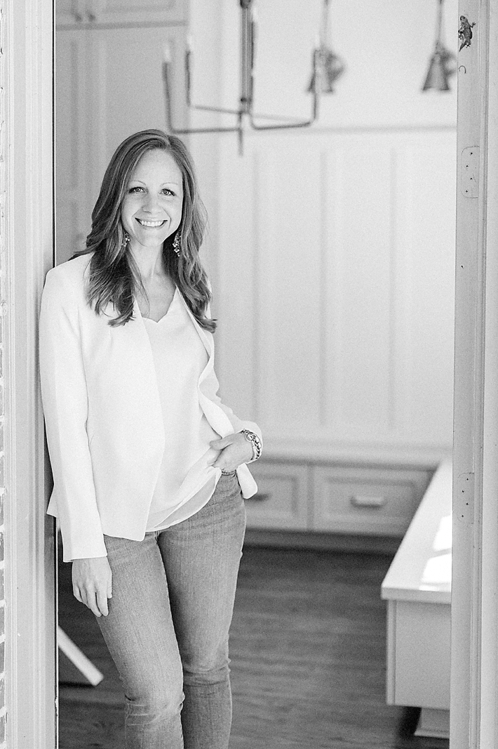 Beautiful black and white professional headshot photo of a Dallas TX business woman posing by a wall smiling at the camera for her branding/headshot session.