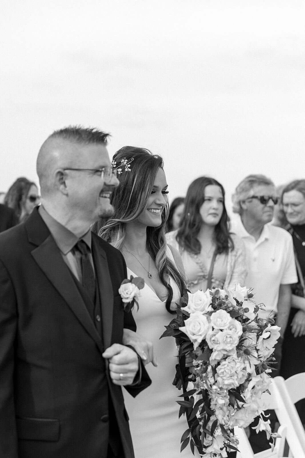 bride walking down the aisle with her dad smiling