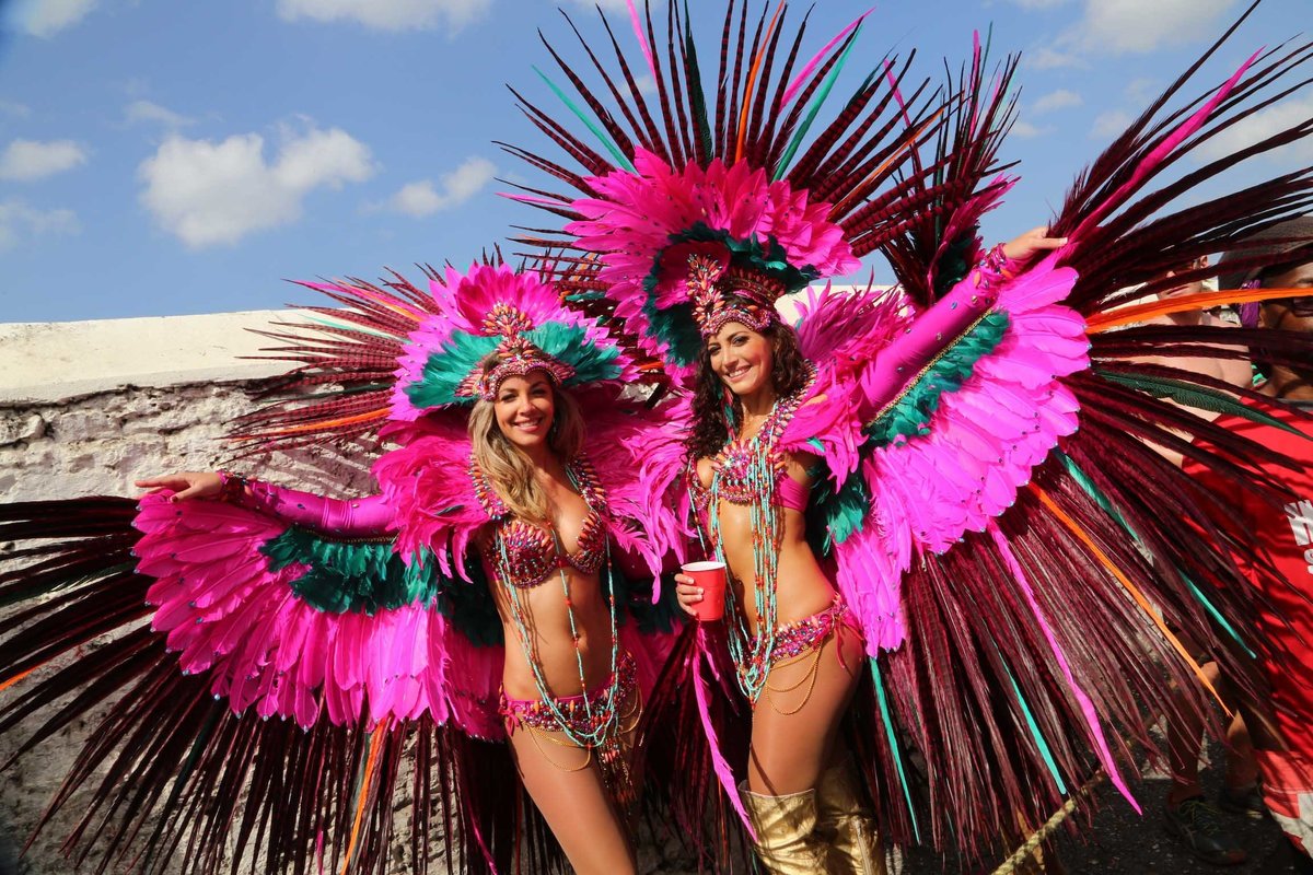 Two ladies playing mas strike a pose in striking pink and feathered costumes. Photo by Ross Photography, Trinidad, W.I..