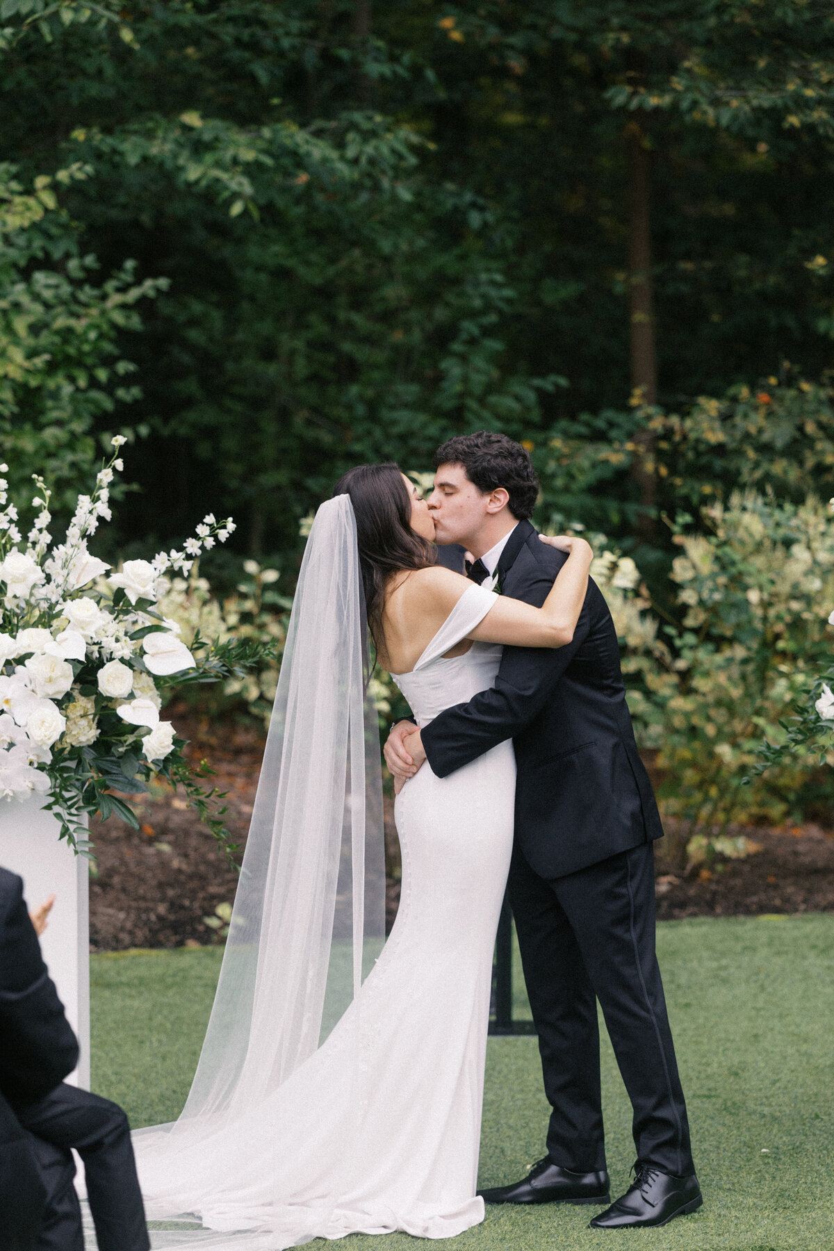 Bride and groom share a kiss at the altar during their elegant black and white wedding at Sapphire Creek Winery.