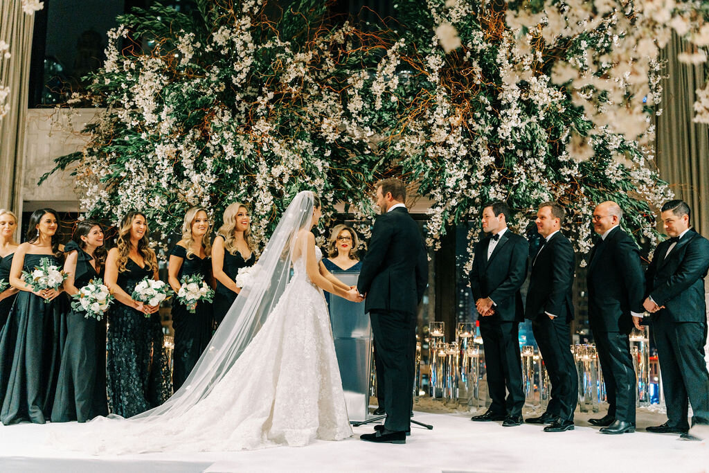 Bride and groom at the alter holding hands under the floral arrangements. 