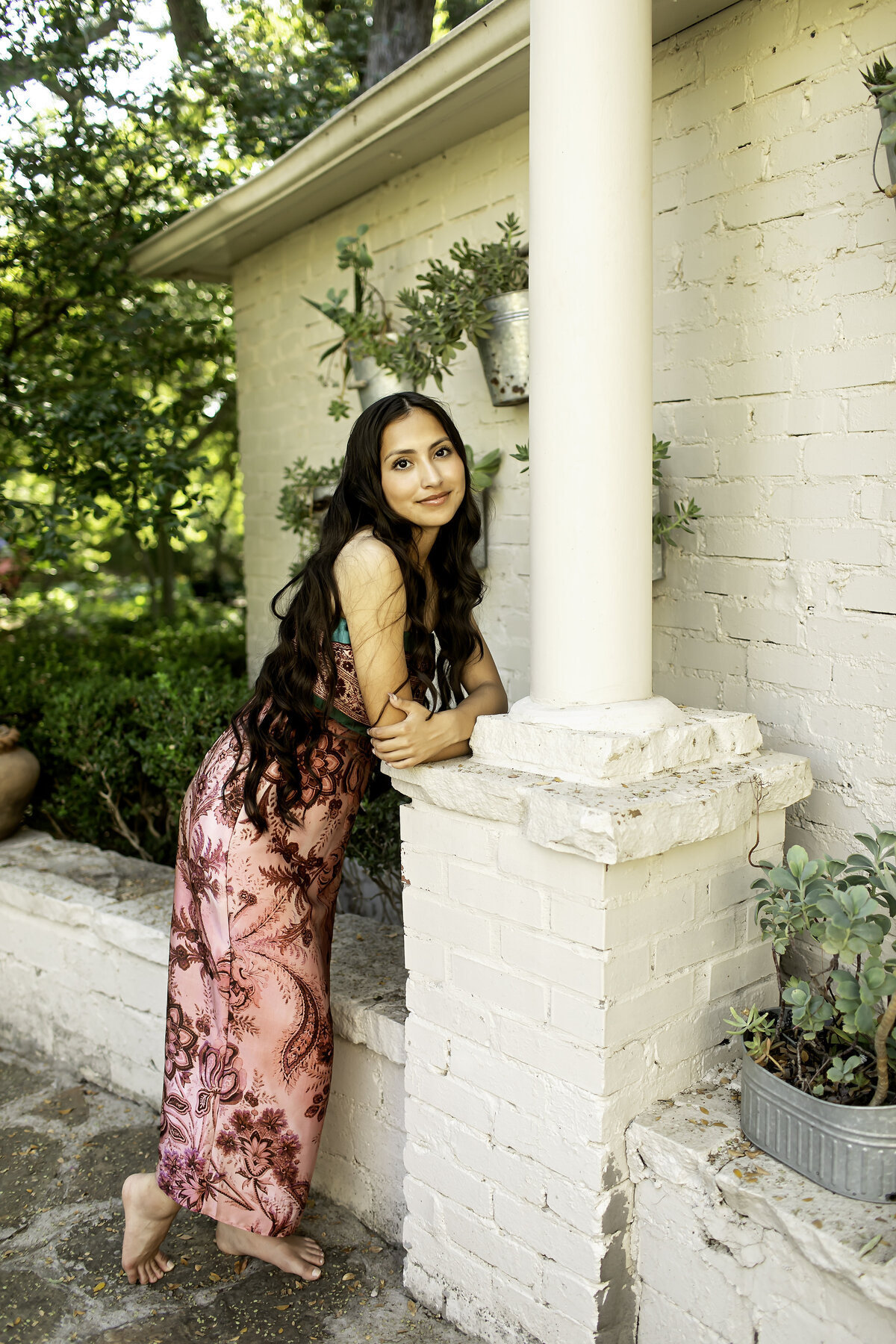 In the tranquil setting of Chandor Gardens, a high school senior smiles as she poses with the vibrant flowers, celebrating the beauty of nature and graduation