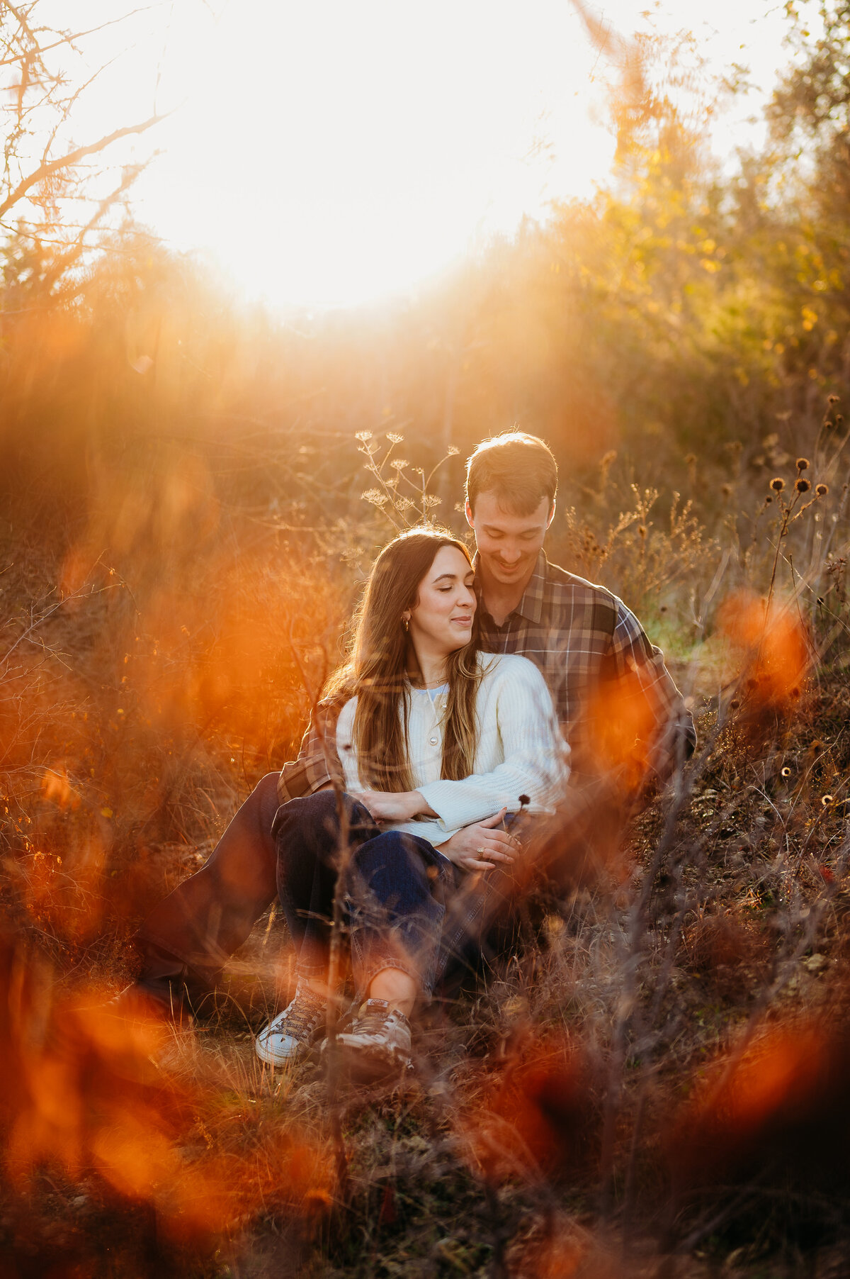 couple sitting in a field surrounded by golden light — heartfelt Fort Worth family photography by Poppy + Blue Photography