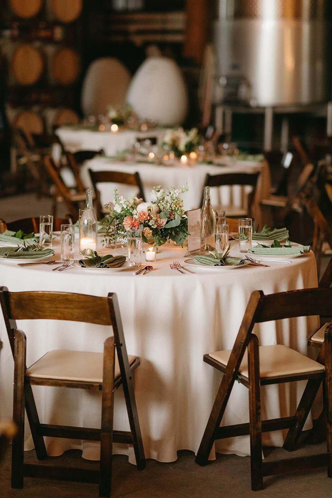 Floral arrangements and candles sit atop tables at a wedding reception at Maysara Winery.