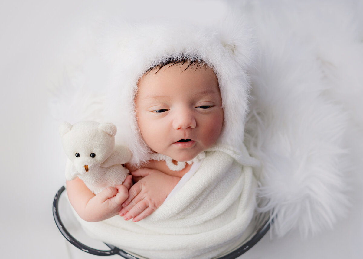 Newborn baby girl, wearing bear hat holding tiny bear during newborn phothosoot in Mount Juliet tennessee photography studio