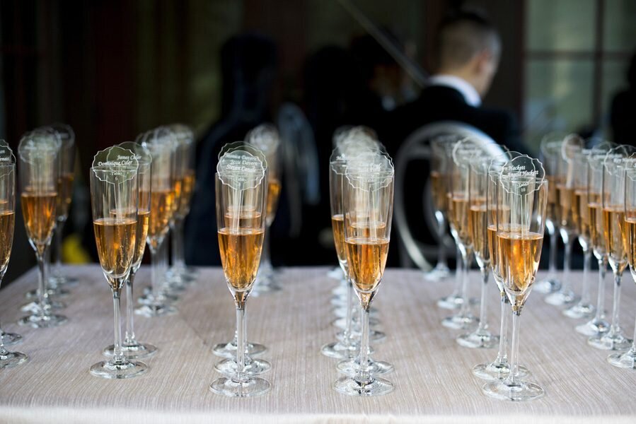 Seven rows of half full champagne glasses are lined up at cocktail hour.