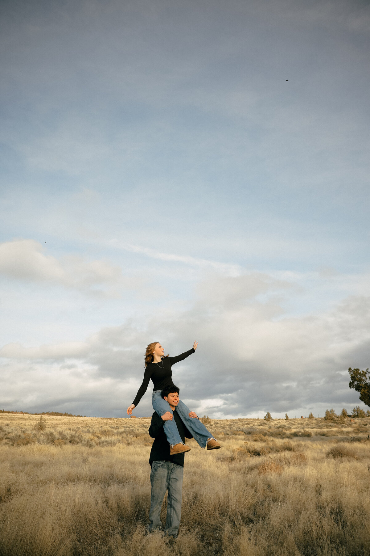 Playful Couple Piggyback Ride in Open Oregon Field During Sunset Engagement Photos