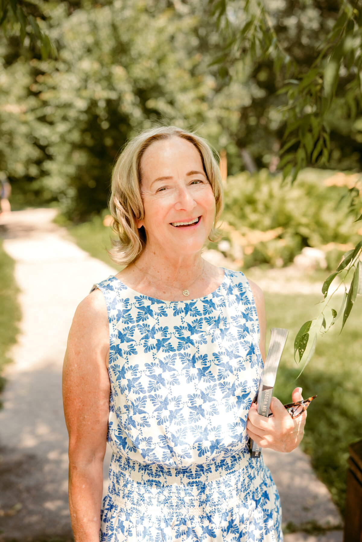Natural light online dating portrait of Linda in a floral dress, smiling in a Minneapolis garden setting.