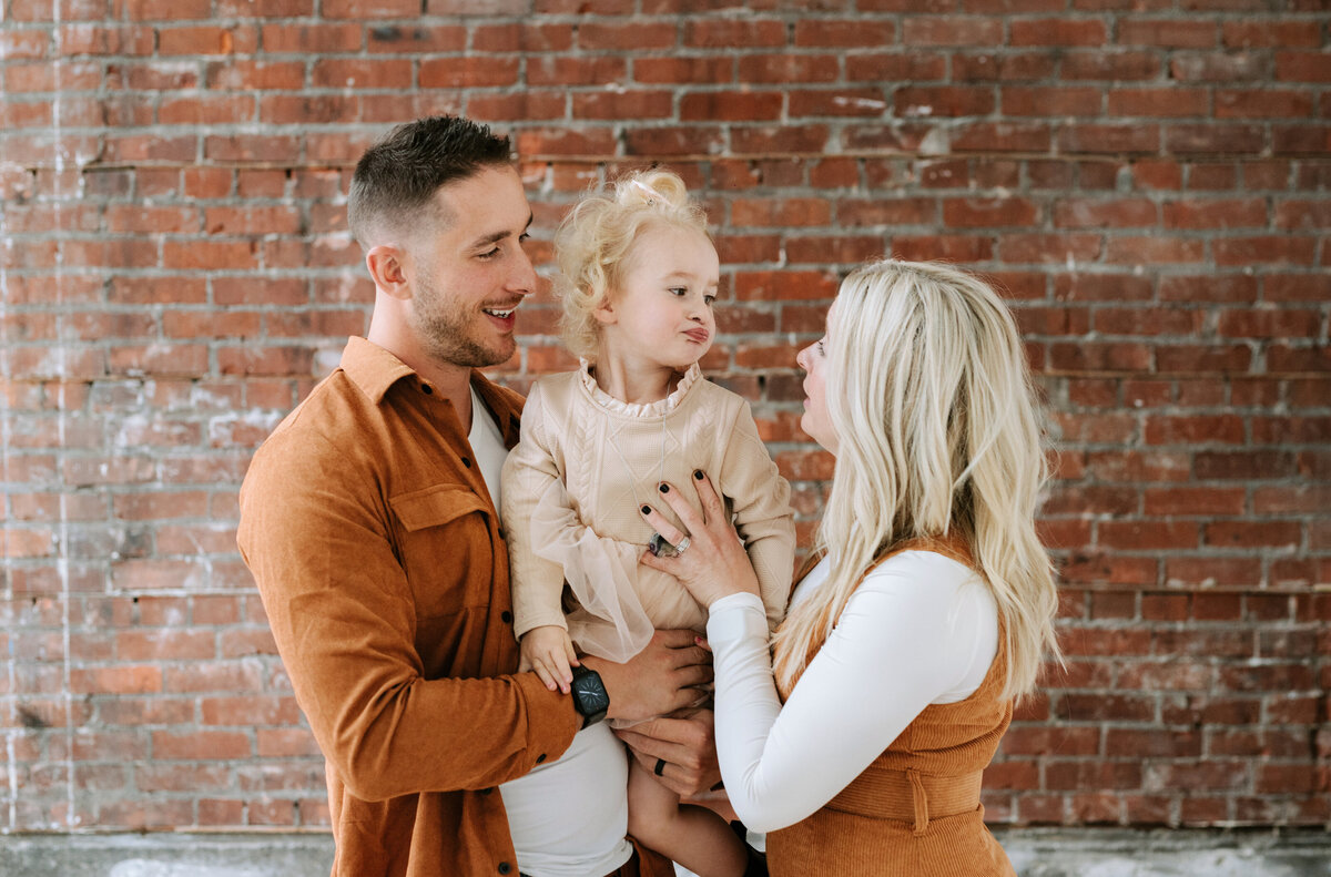 A family of three share a candid moment at Studios at Vic Park in Calgary, Alberta