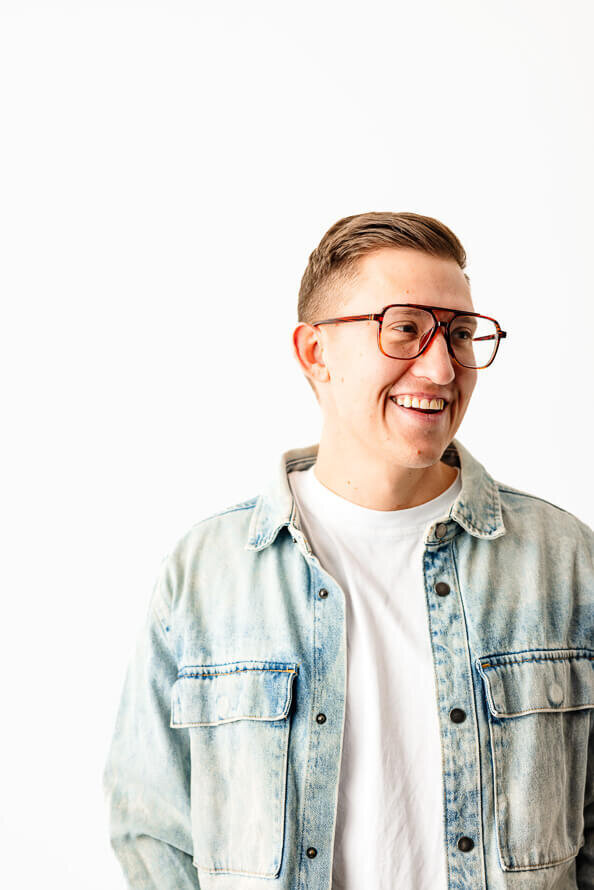 Man in jean jacket smiles off to side of camera.