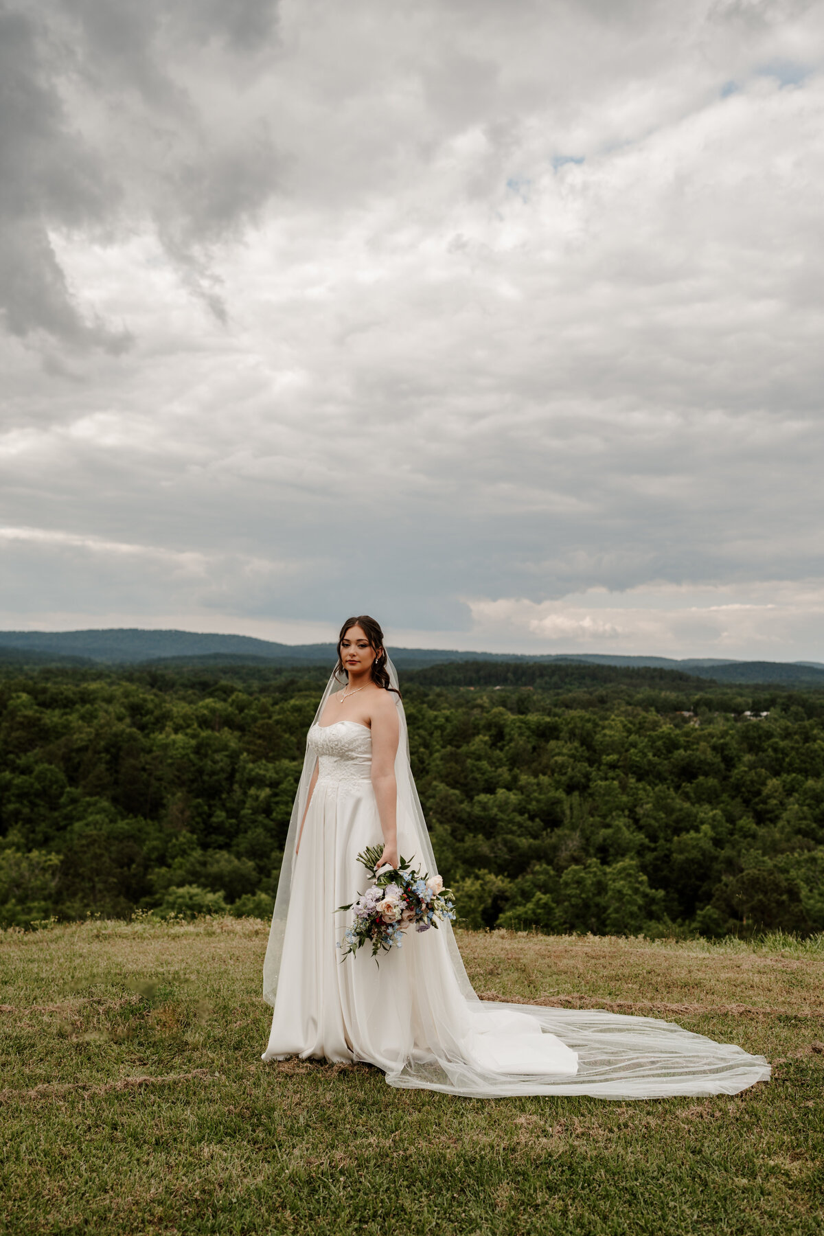 Bride standing on a hilltop with mountains in the distance at a Arkansas wedding—captured in a cinematic, story-driven style by Nashville photographer Kenzie Digitized.