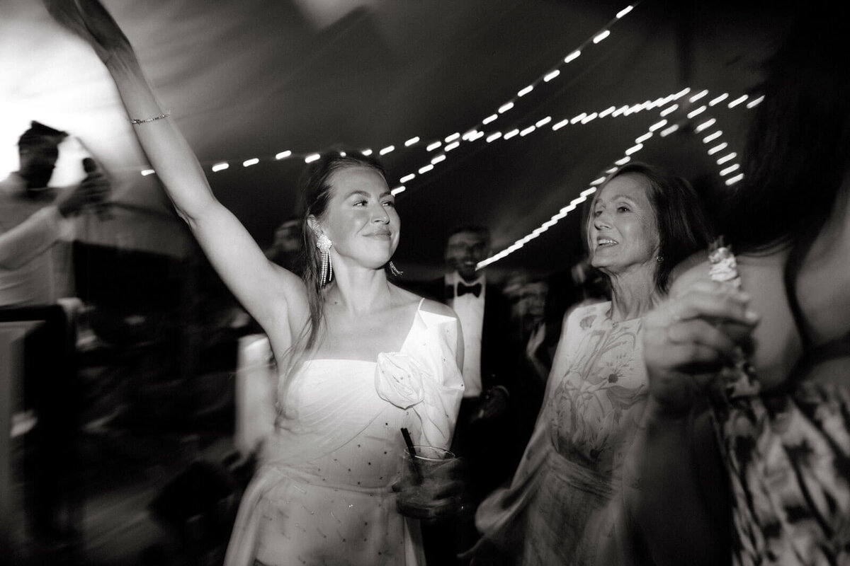 The bride and her mom are having a good time partying with the guests in a wedding reception at The Ausable Club, NY. Image by Jenny Fu Studio
