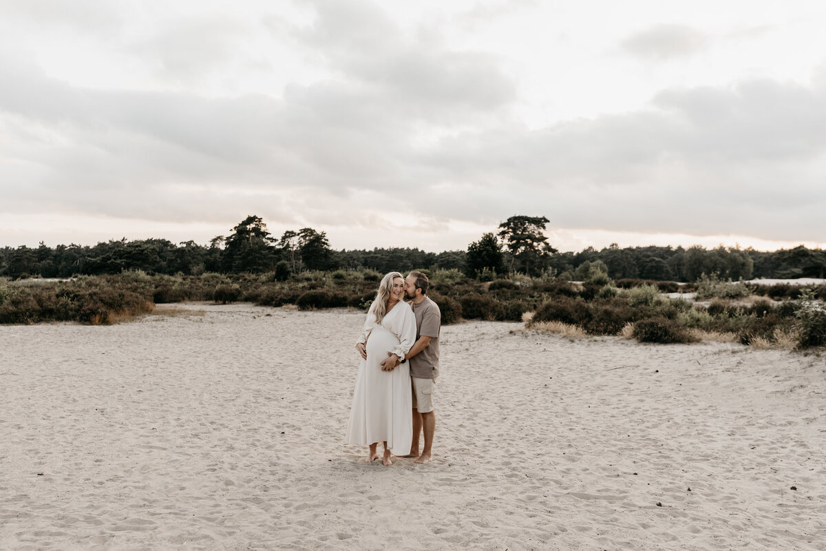 Foto van knuffelend stel tijdens een zwangerschapsshoot in de Soesterduinen.