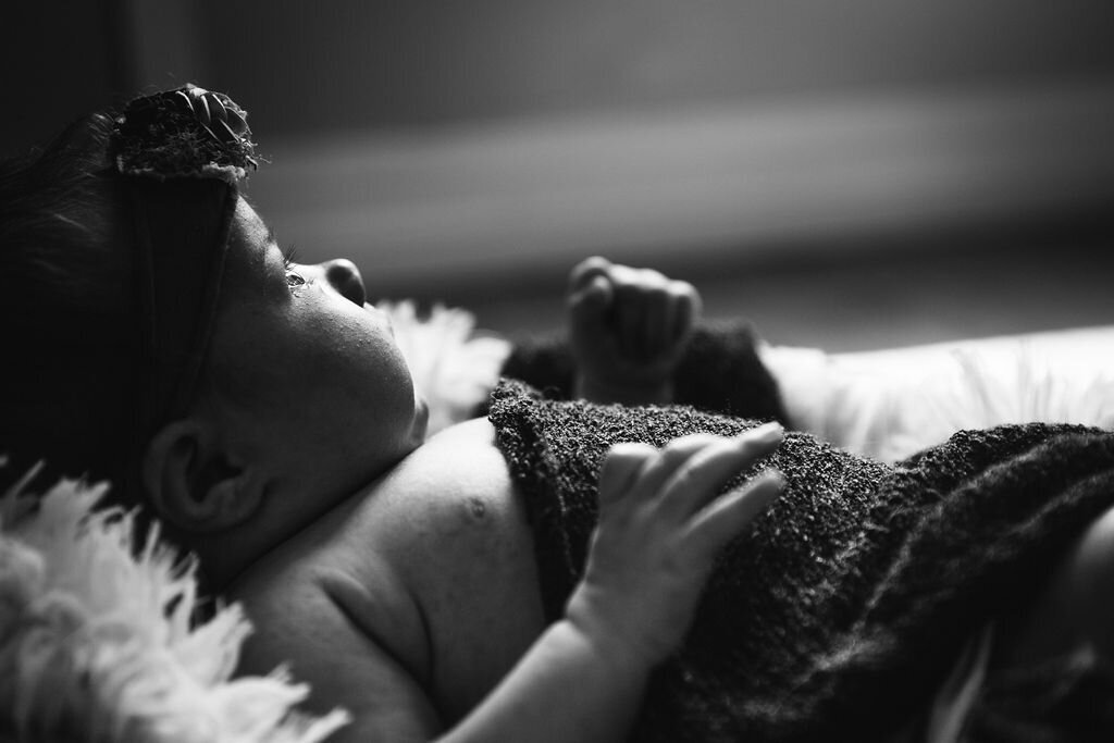 Newborn baby looks out a window