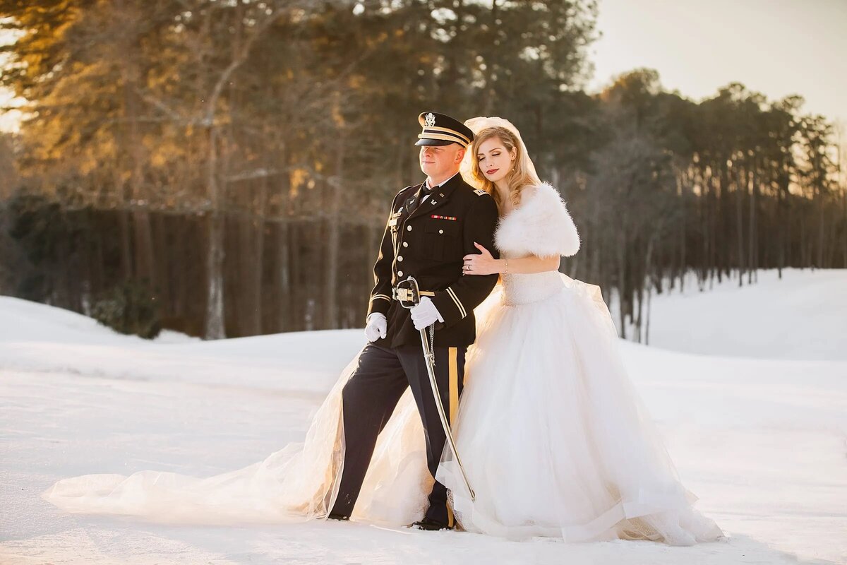 A military groom in uniform and a bride in a winter setting create a romantic contrast against a snowy landscape.