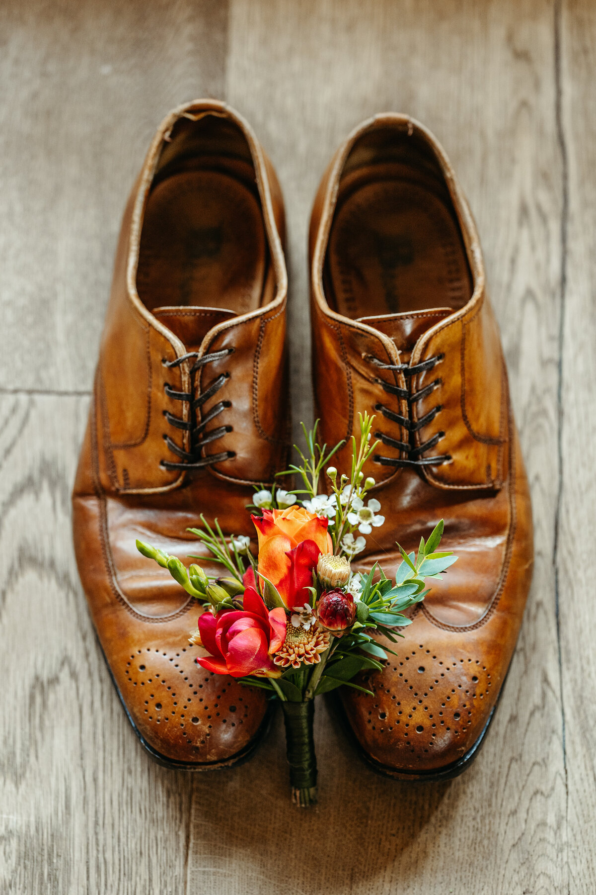 Groom’s leather shoes and boutonniere flat lay