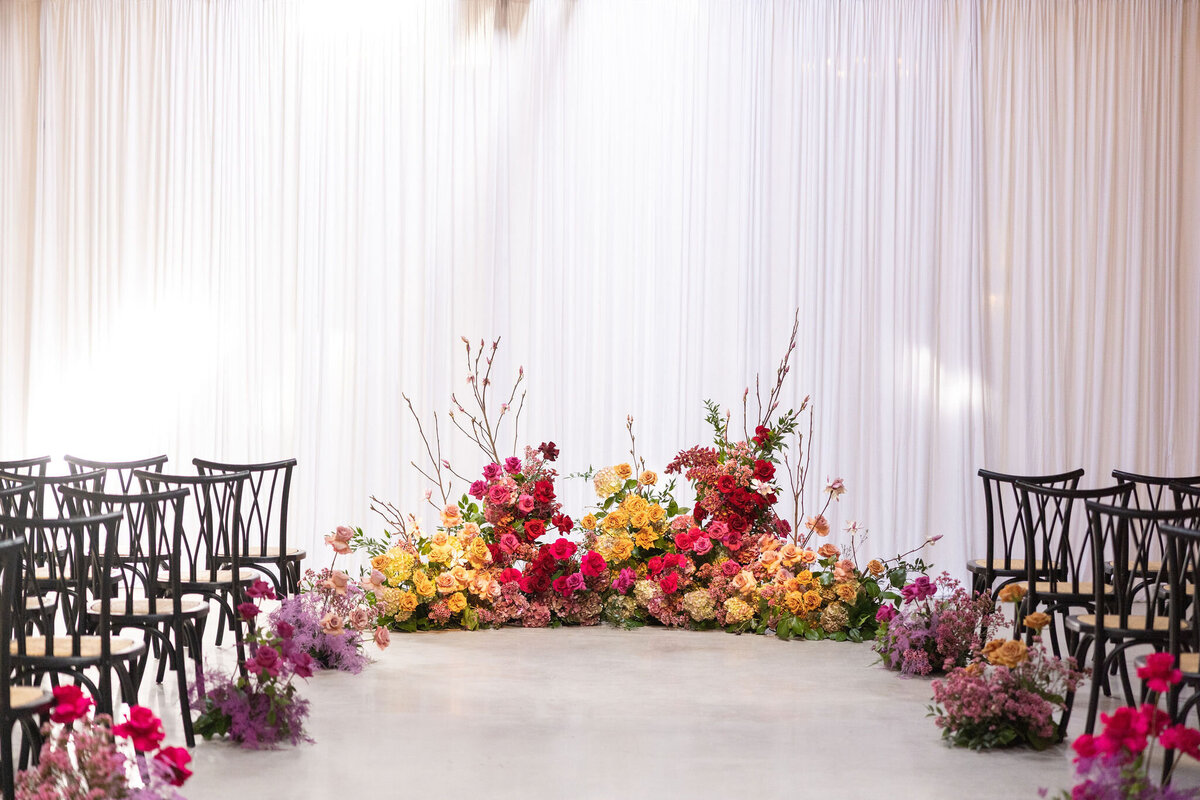 up to 200 guests in Locus for ceremony with draped backdrop and statement ground floral arch piece