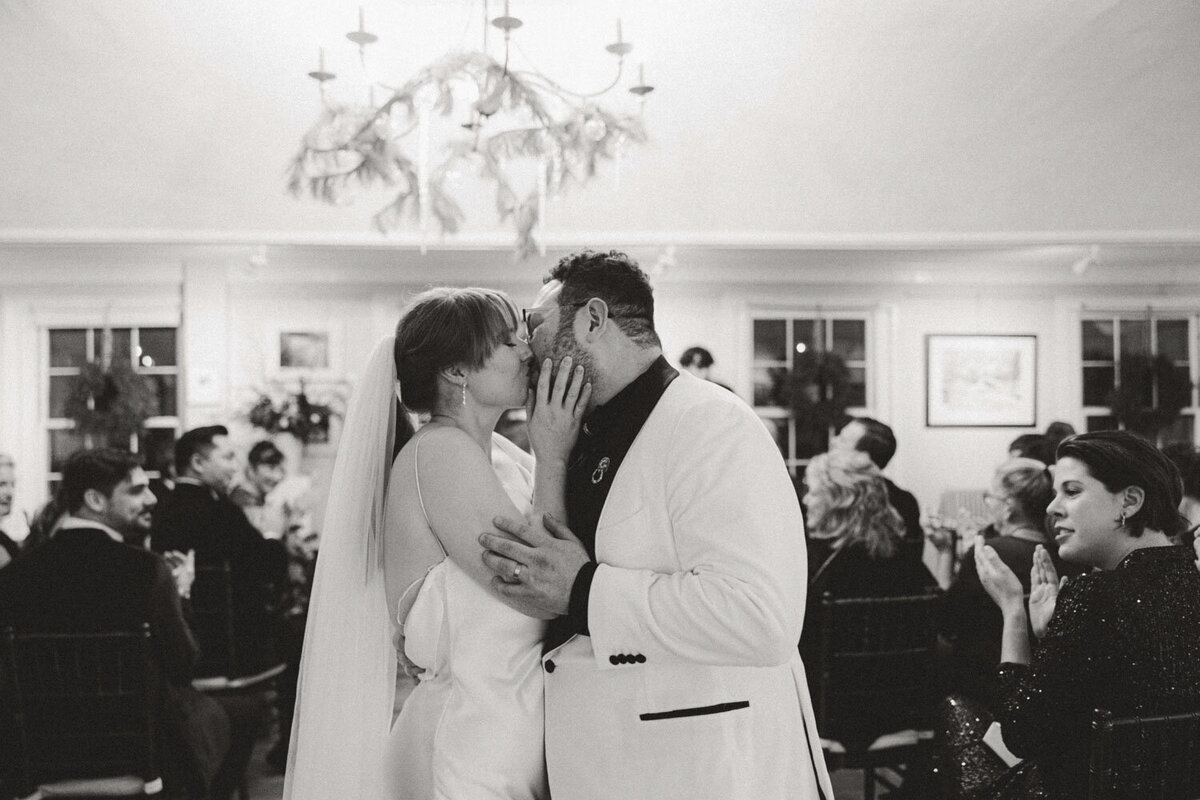 Black and white photo of bride and groom kissing on their wedding reception
