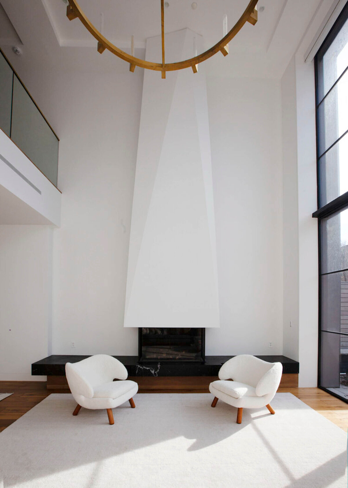 White single accent chairs in living room with large black fireplace in living room.