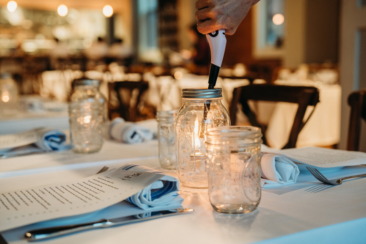 waiter lighting mason jar candle in restaurant in boston