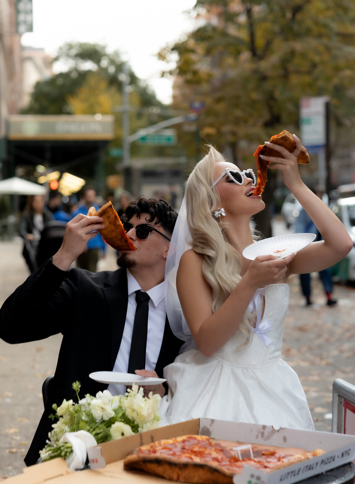 Bride and groom toasting their pizza slices together in celebration of their NYC elopement.