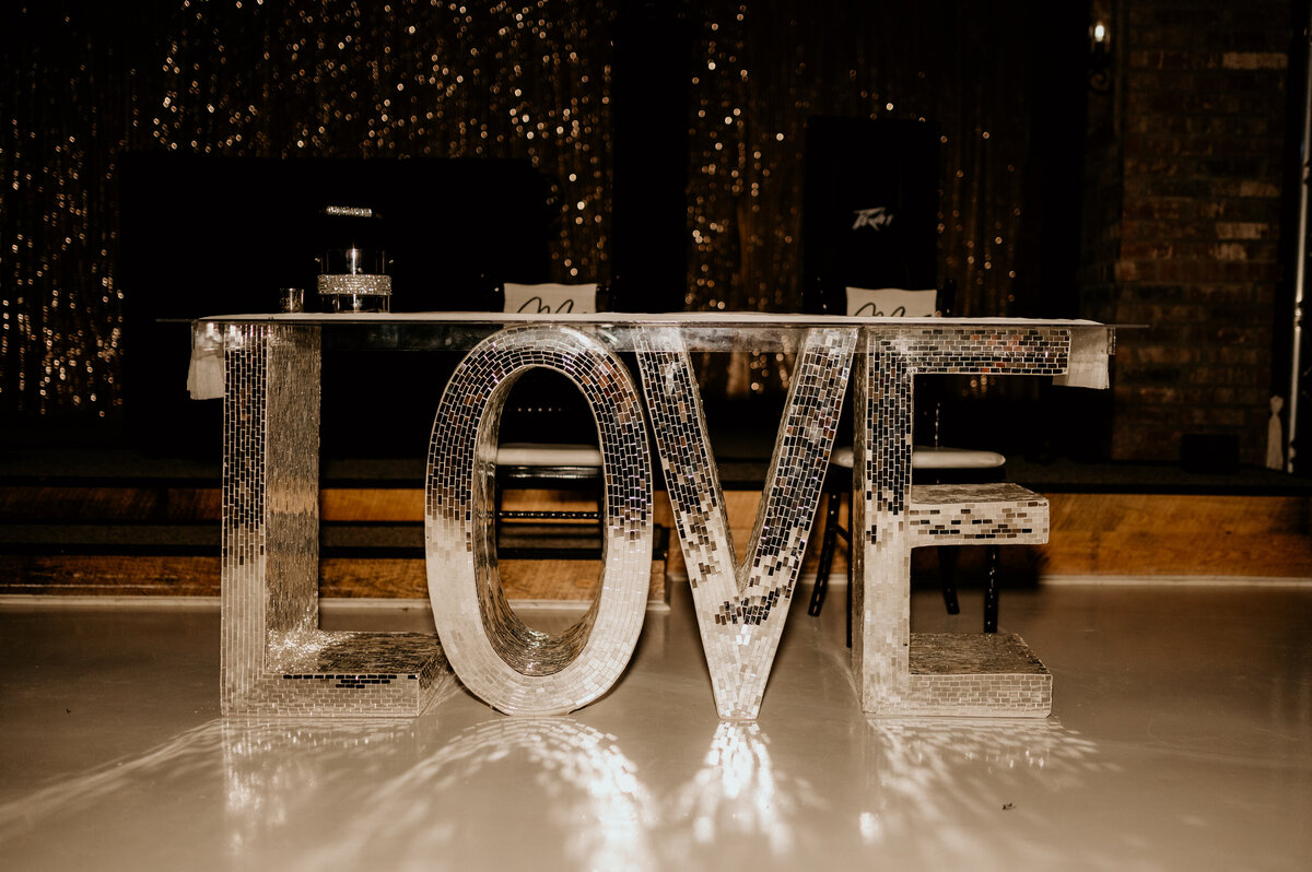 disco wedding decor with the word "love" covered in little mirrors for a disco effect