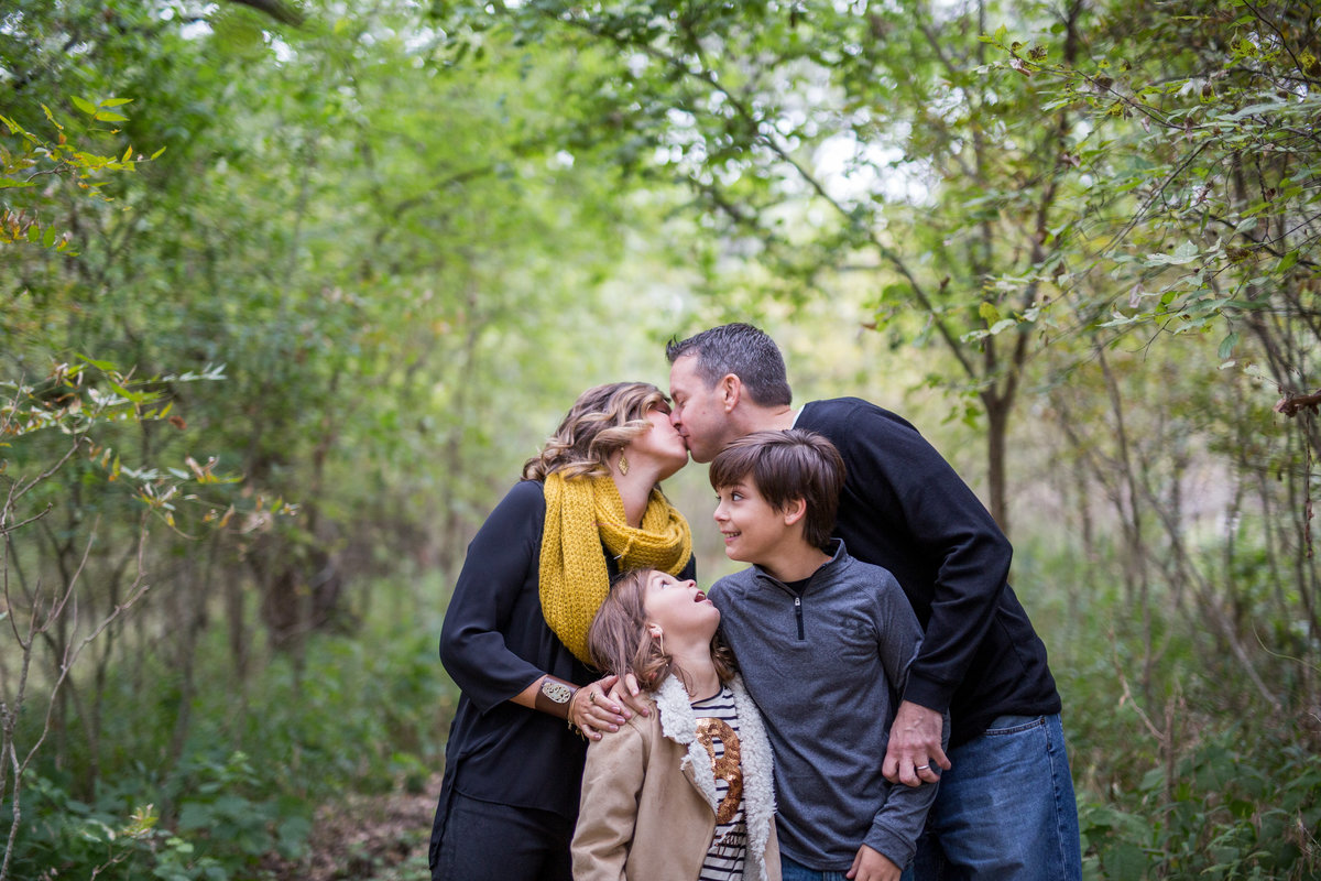mom and dad kissing and children looking at them by San Antonio photographer Expose The Heart