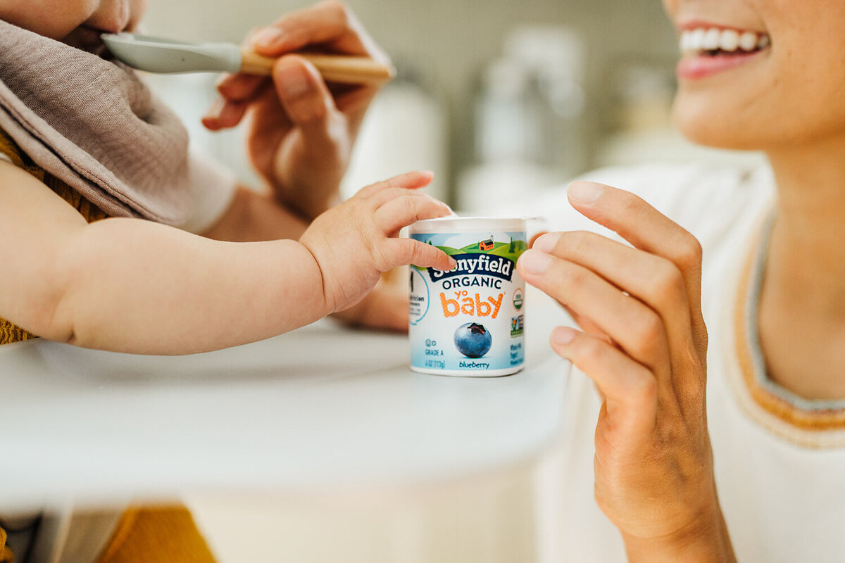 close up of baby hand with yogurt cup during commercial image session