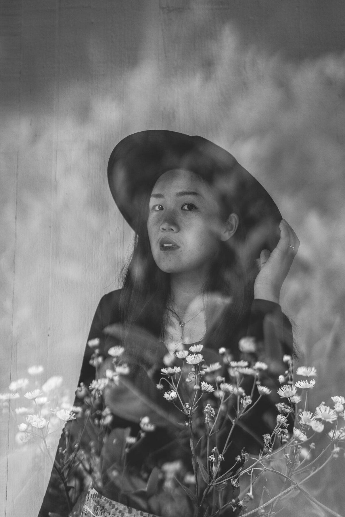 Double exposure image at Bay Area creative branding session of woman holding hat with florals in front