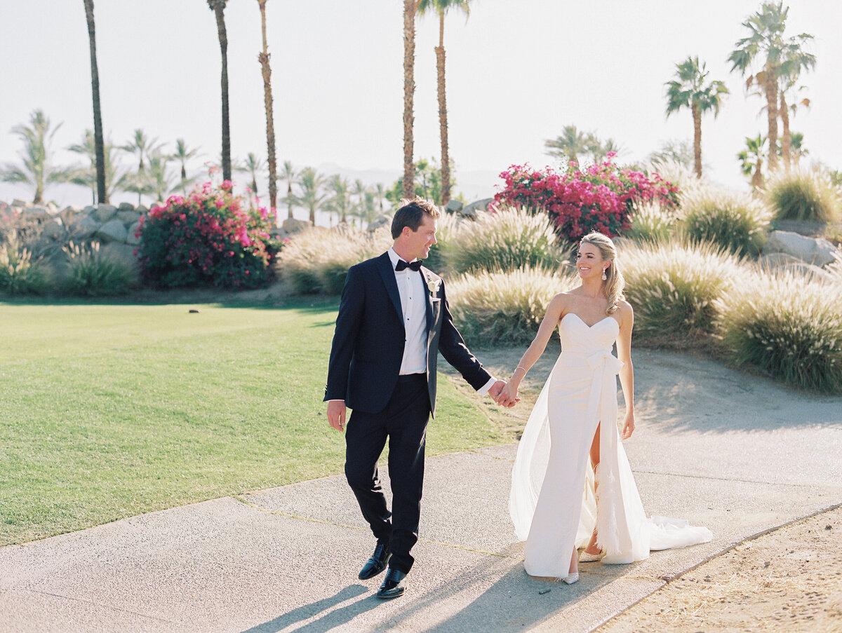 couple walking at la quinta resort and spa in white wedding dress with feathers