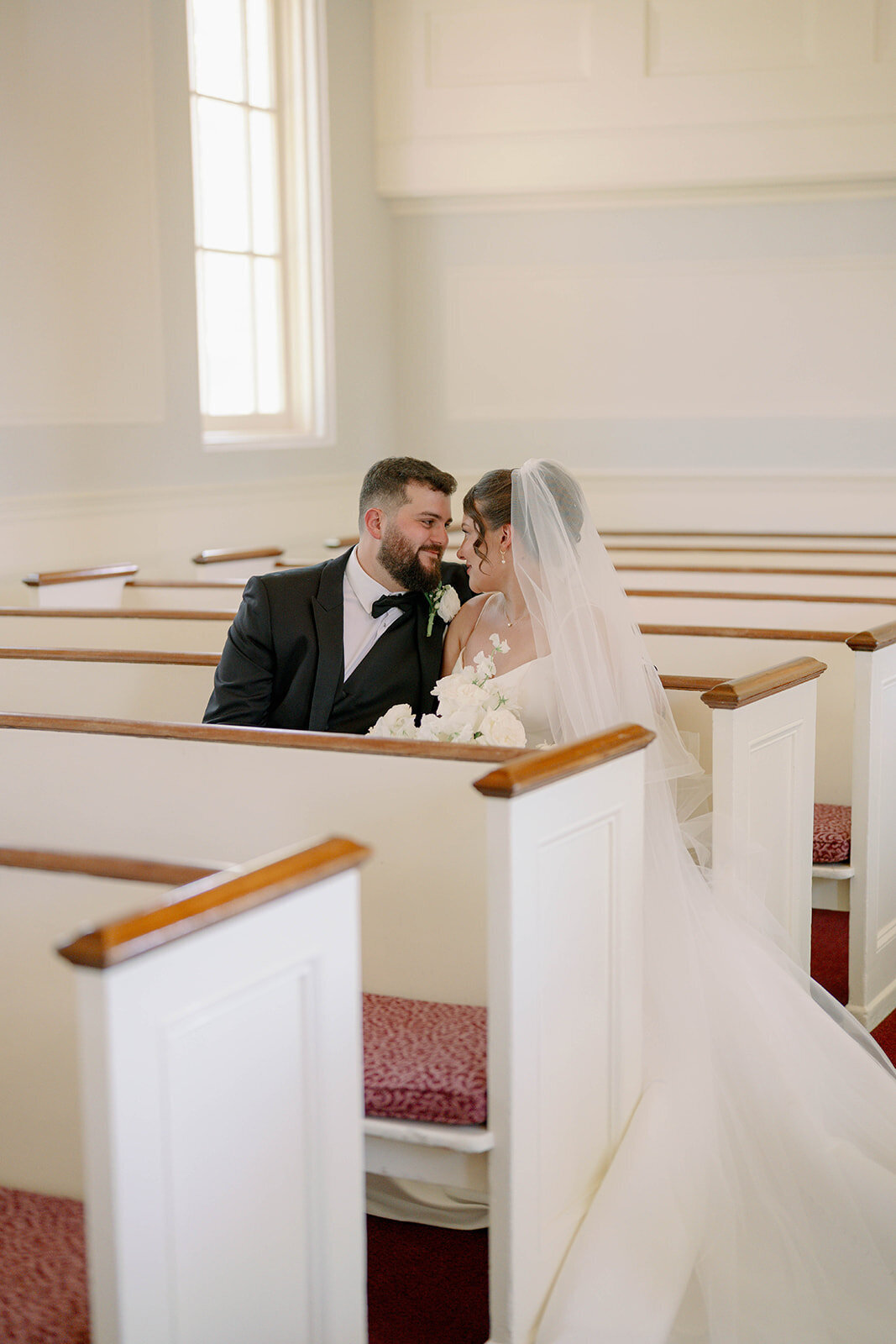 Bride and groom sitting together in a Martha-Mary Chapel pew after their ceremony, intimate church portrait.