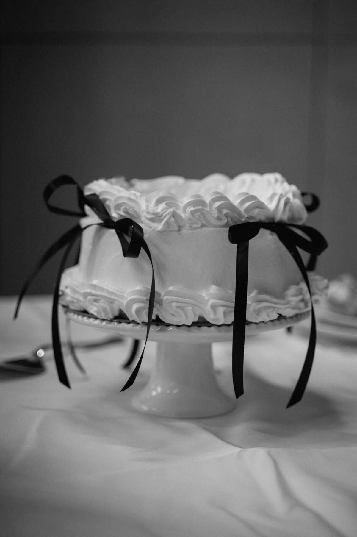 Editorial black-and-white photo of minimal wedding cake with ribbon details in Banff.