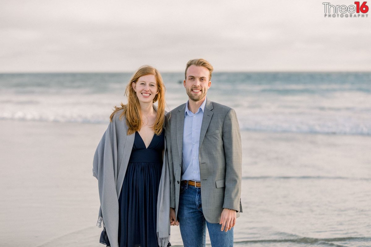 Engaged couple stand together during a beach photo shoot