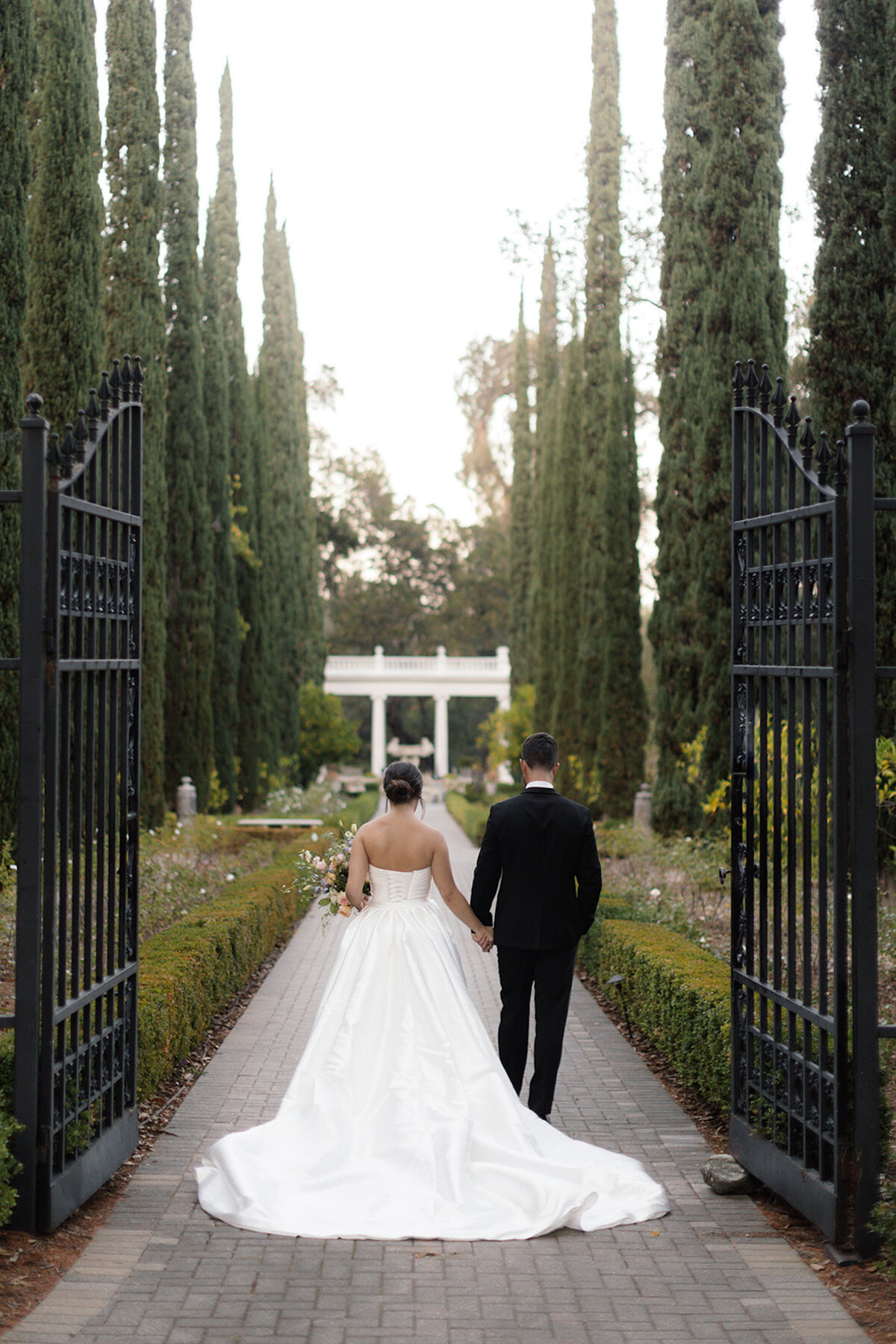 Bride and groom walking through iron gates