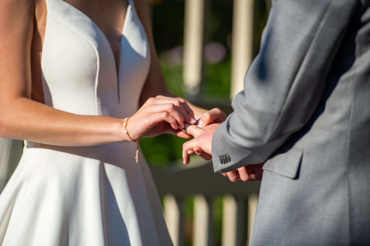 a closeup photo of hands as a bride putting a wedding band on her groom during their Ottawa wedding ceremony