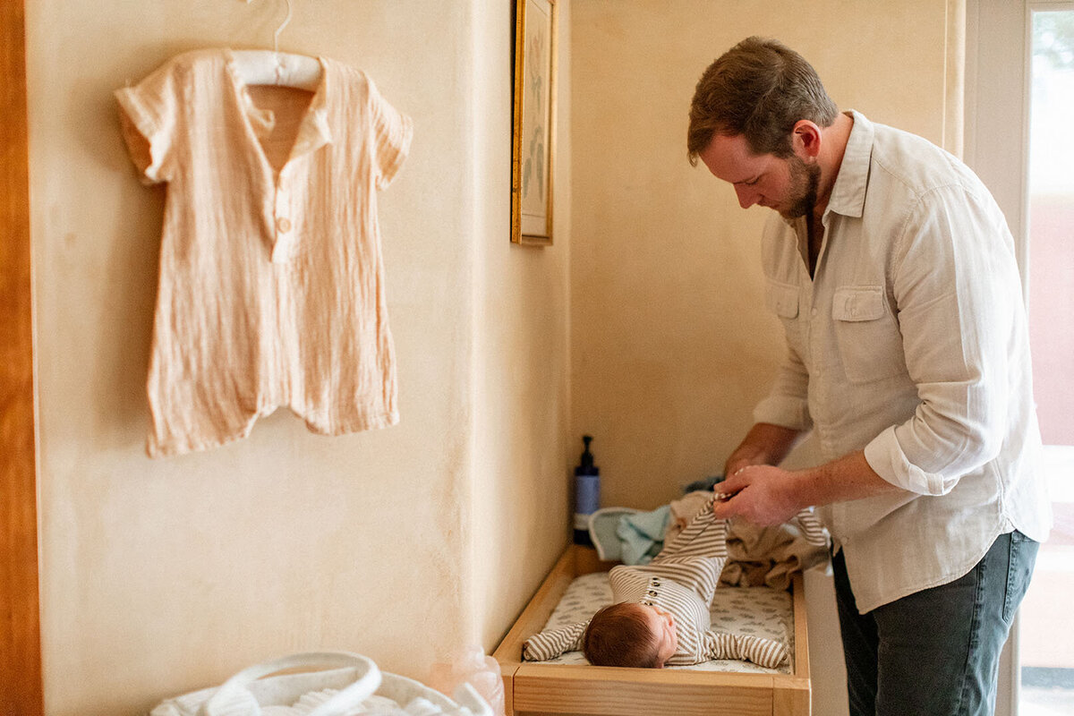 Father changing newborn baby's diaper - Sara James documents authentic parenting moments and daily newborn care during real-life lifestyle photography sessions in San Antonio Texas homes