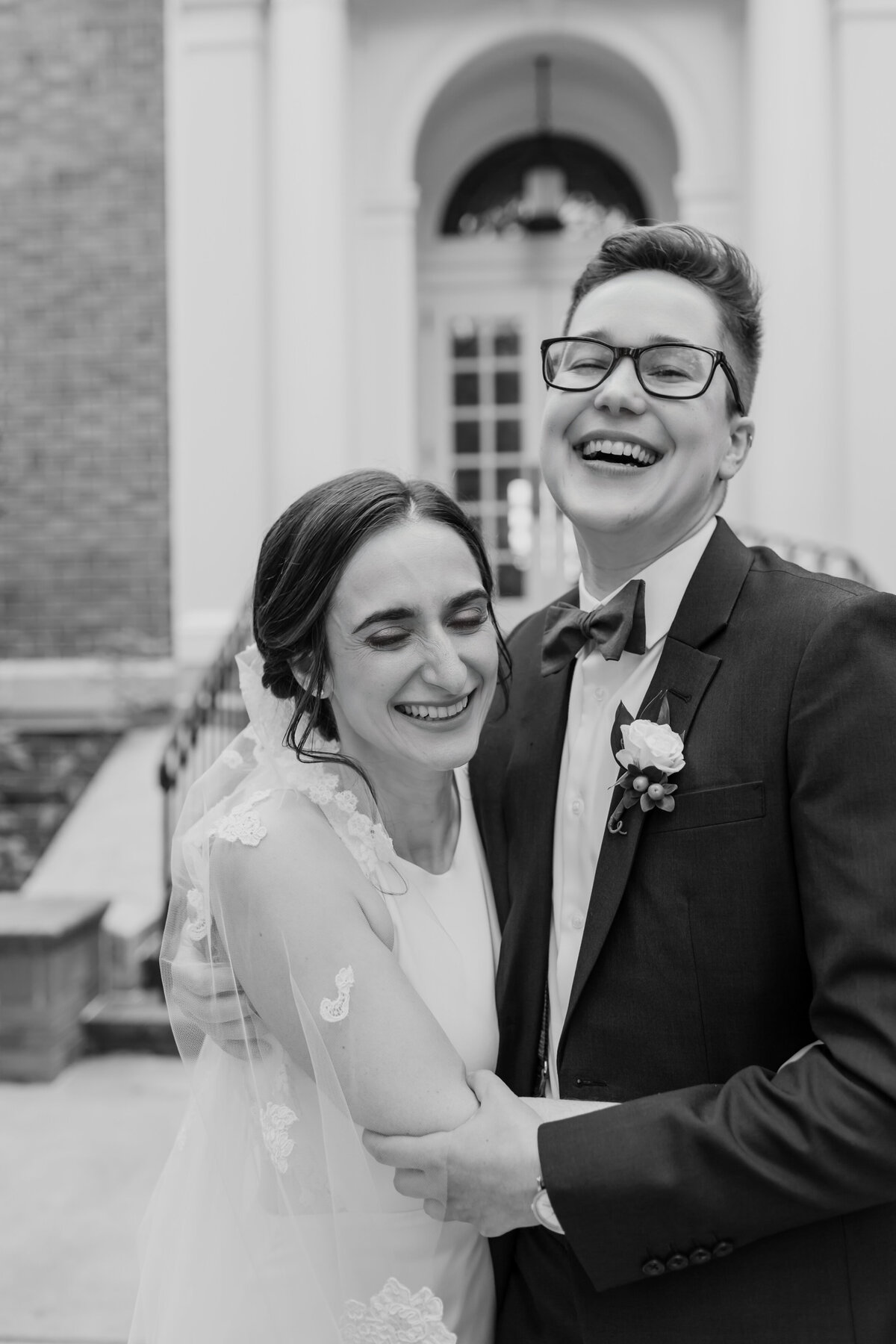 A black and white candid of an LGBTQ+ couple laughing on their wedding day. Captured by Fort Worth wedding photographer, Megan Christine Studio