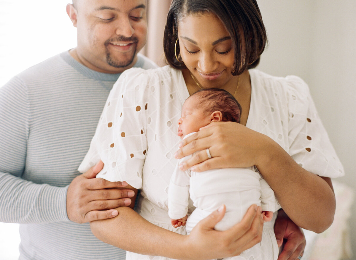 New parents snuggle their first daughter closely. Image by Raleigh newborn photographer A.J. Dunlap Photography.
