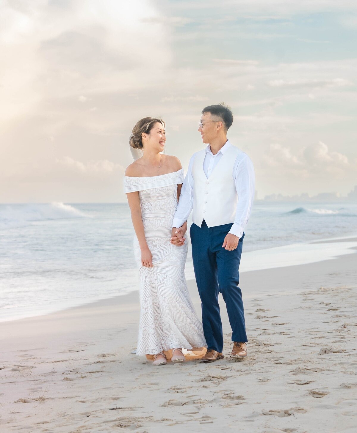 a newly married couple walks on the beach in Cancun