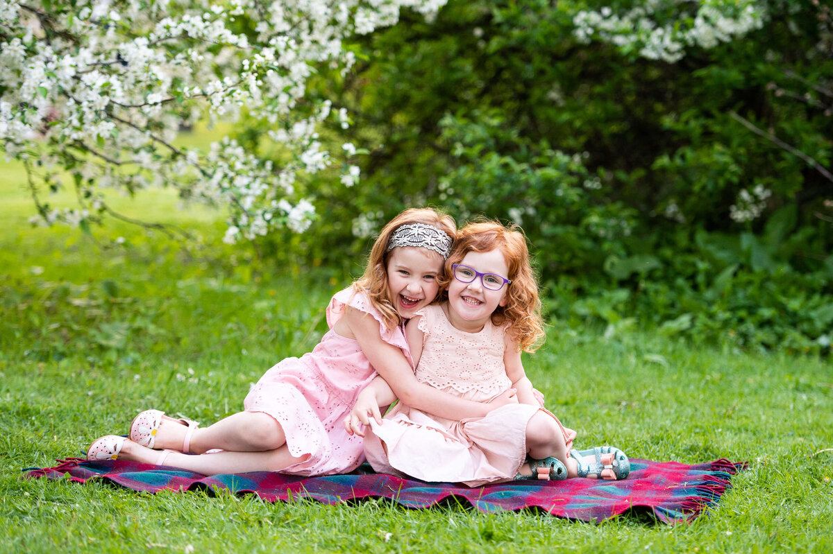 Ottawa family photography of a two sisters sitting on a blanket laughing and smiling