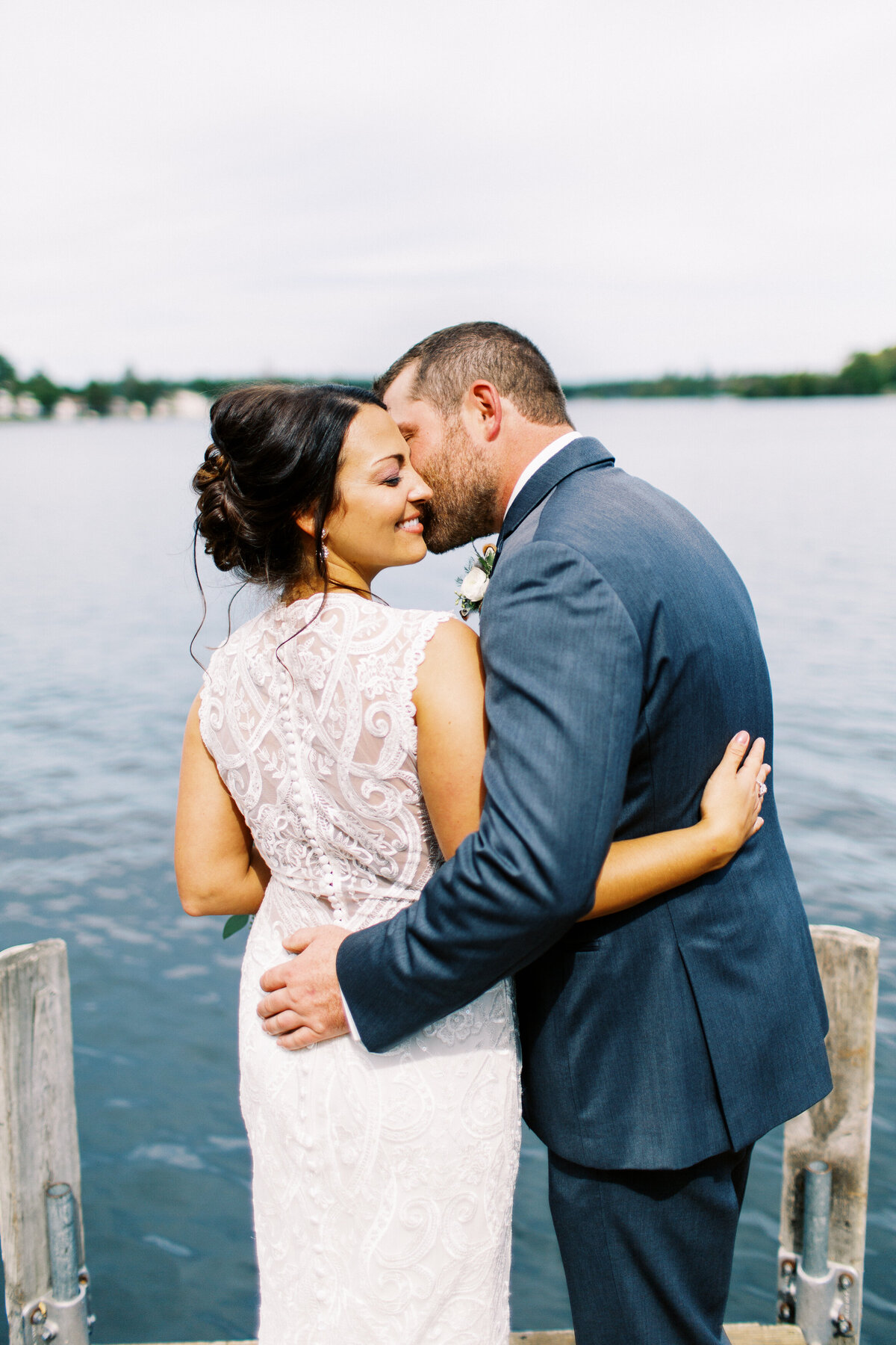 Groom kissing his bride by the lake