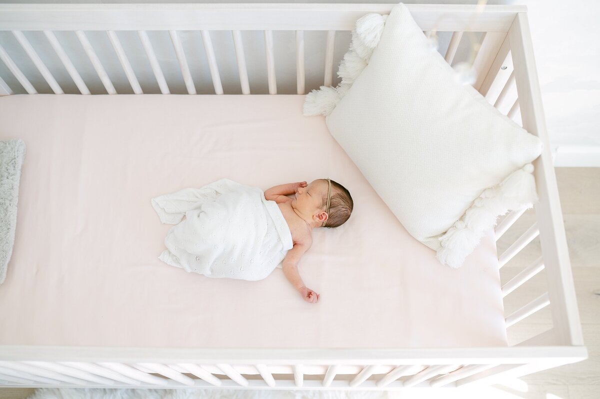 Photo from above of baby laying in a crib