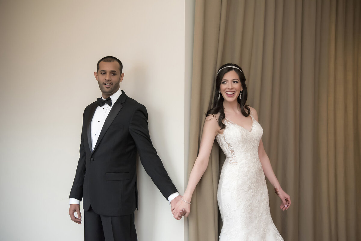 Newlyweds holding hands around a corner 