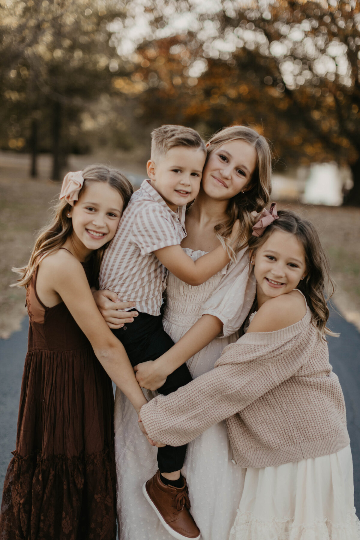 Four siblings sitting close together and smiling at the camera.