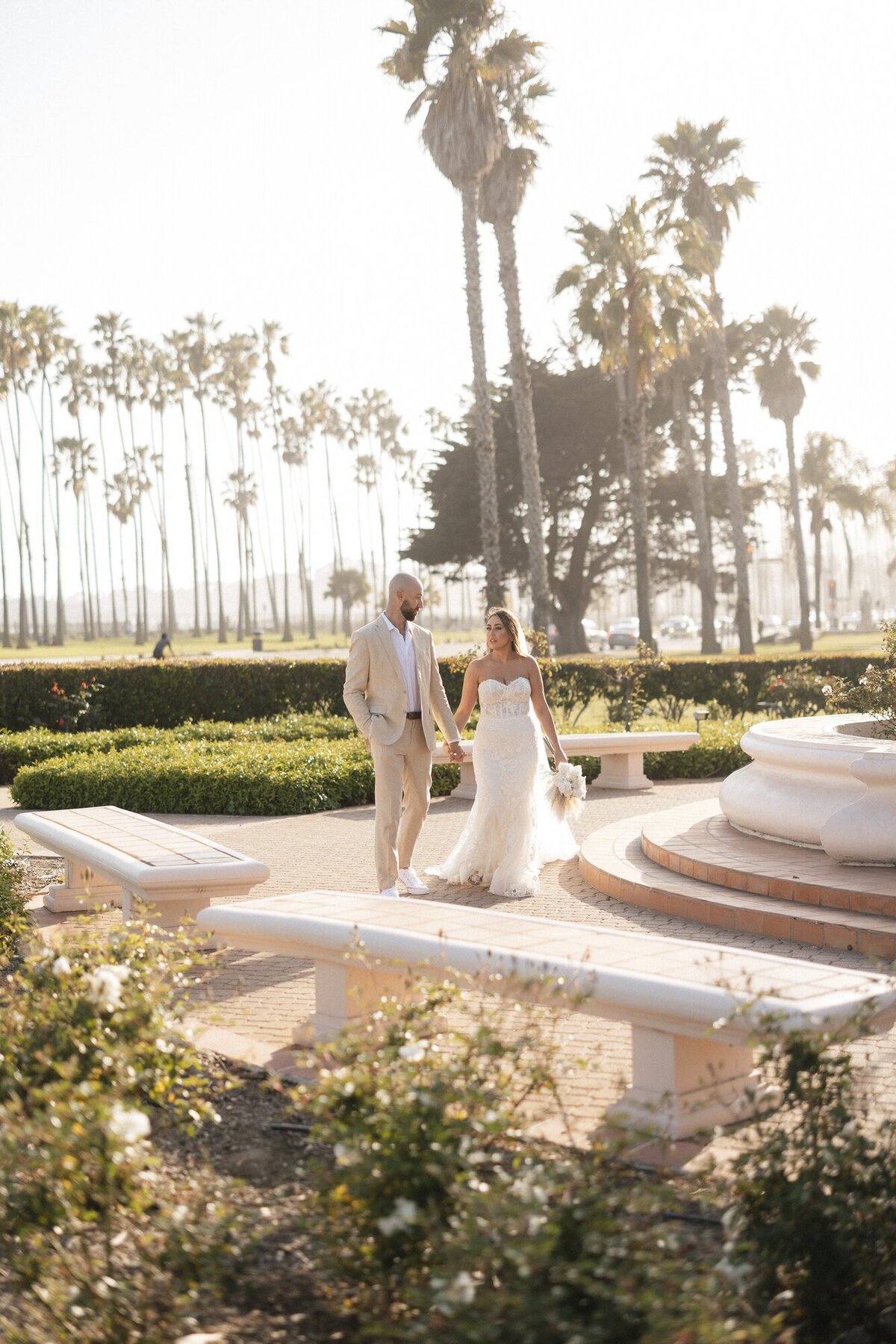 Bride and groom holding hands at sunset at Hilton Beachfront Resort Santa Barbara