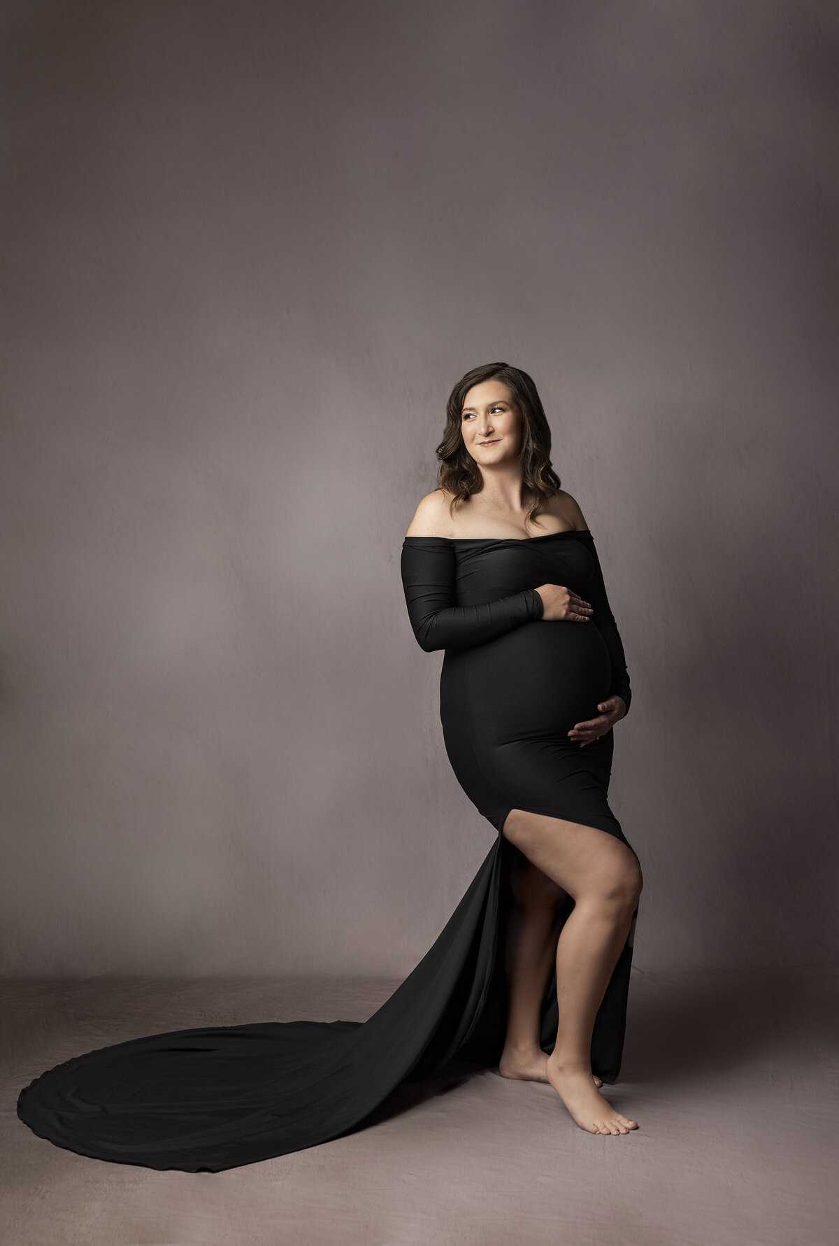 mother in black dress holding pregnant belly
